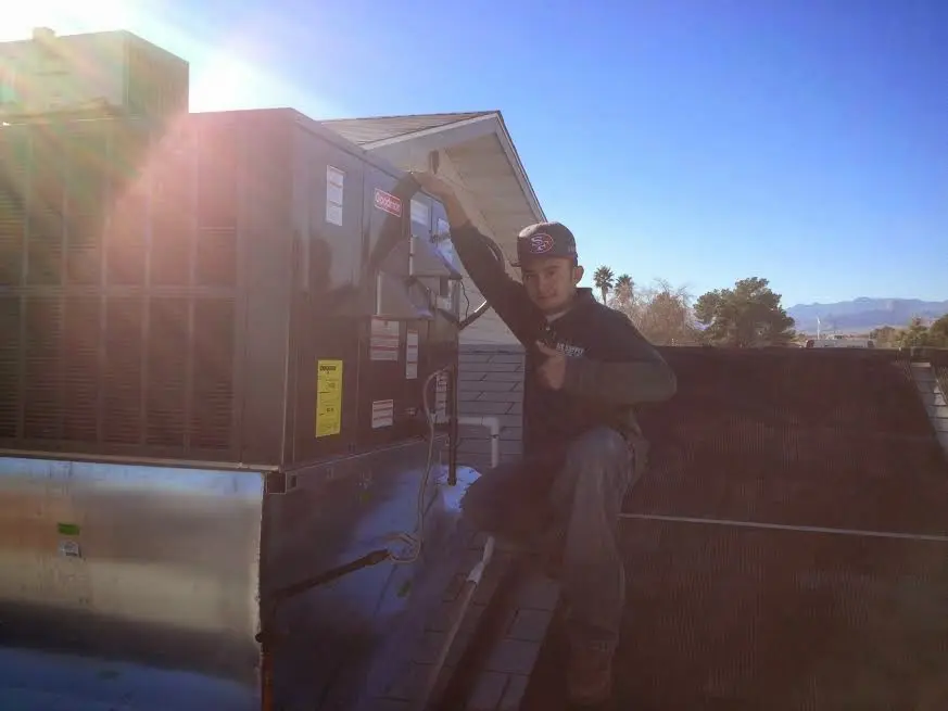 HVAC technician performing Air Duct Cleaning on a rooftop unit in Monroe